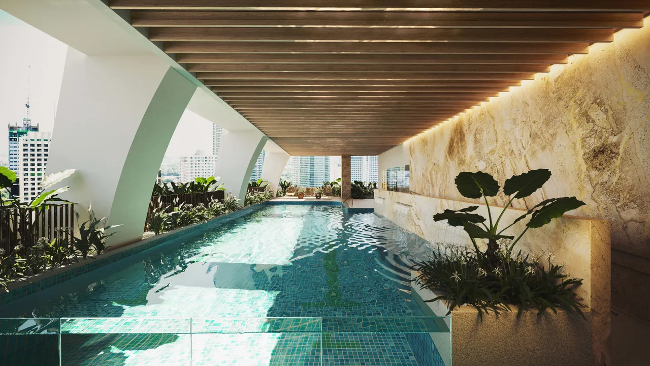 The planted lap pool under a timber ceiling at Eluria, open to the Makati skyline. Artist's perspective.