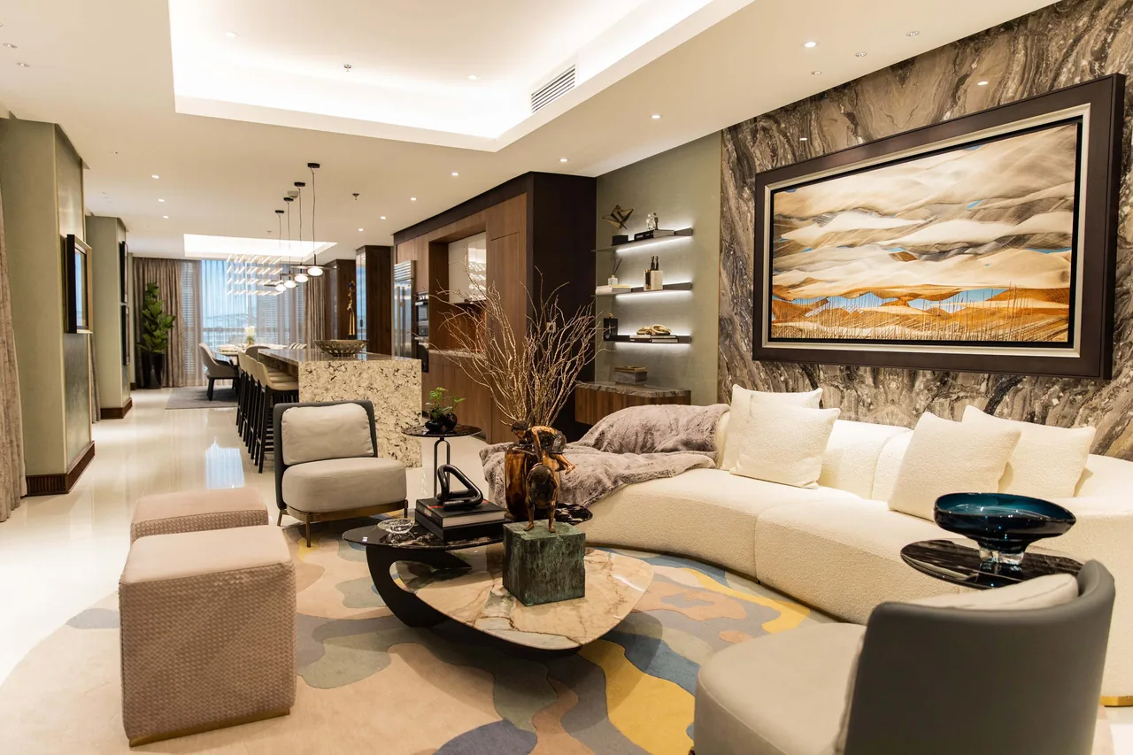 A furnished living area in the Eluria show suite, with stone, warm timber and a curved sofa.