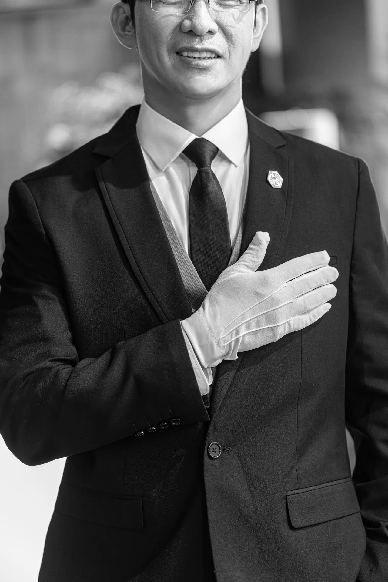 An Eluria Hospitality Director in white gloves, hand to chest.