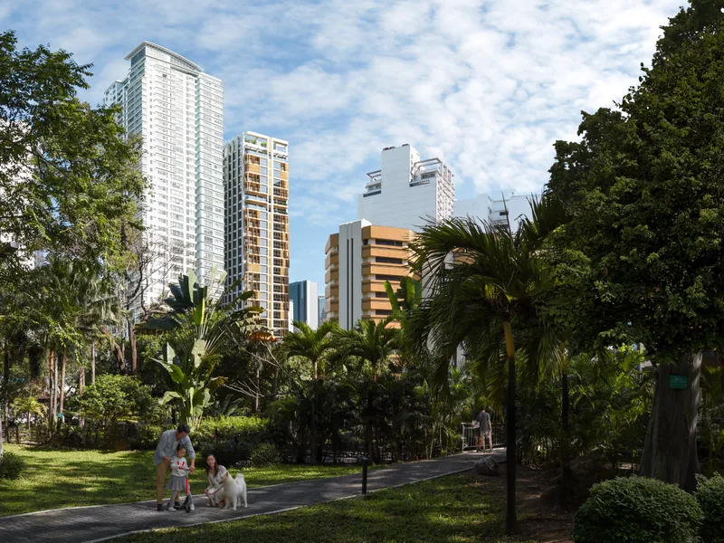 The park at Legazpi Village, palms and walking paths with the Makati towers behind.