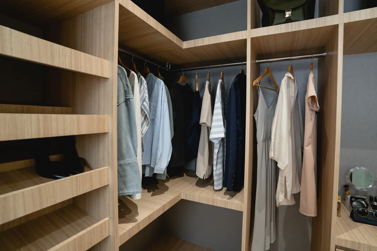 A walk-in wardrobe at Lucima in pale timber.