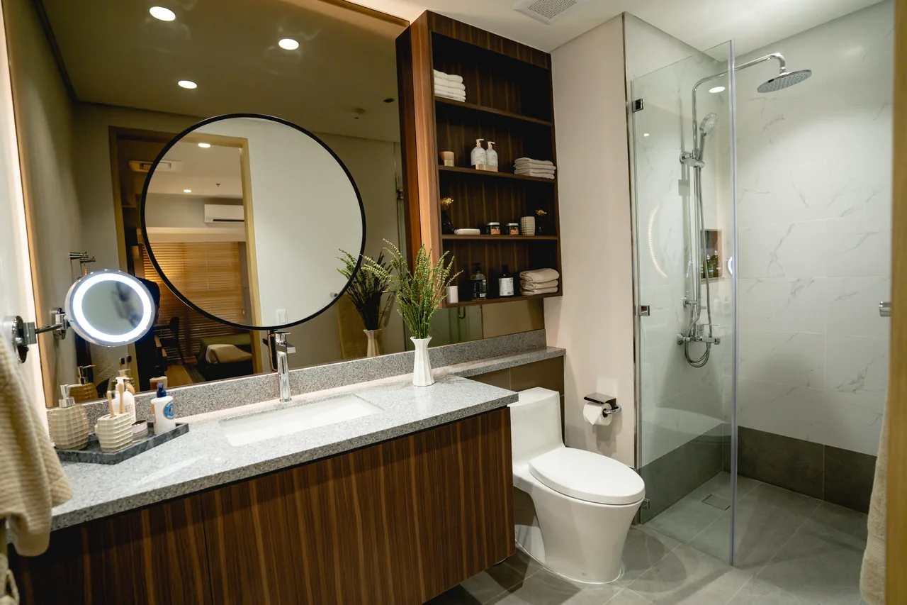 A bathroom at Lucima with a round mirror and walk-in shower.