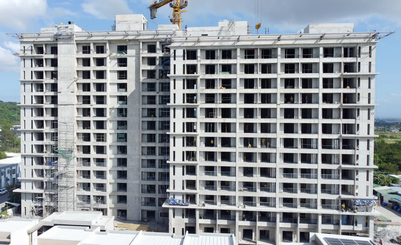 Una Apartments under construction, the concrete frame topped out against the sky.
